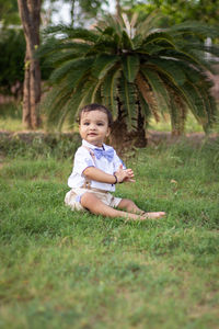 Portrait of boy sitting on grassy field