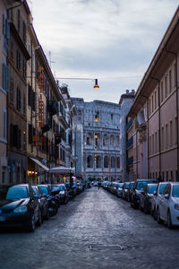 Cars on city street against sky