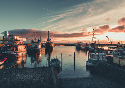 Boats moored at harbor during sunset