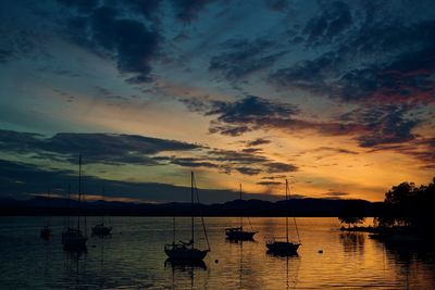 Silhouette of boats in sea at sunset