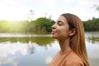 Side view of young woman with closed eyes enjoying breathing in tropical park of brazil.