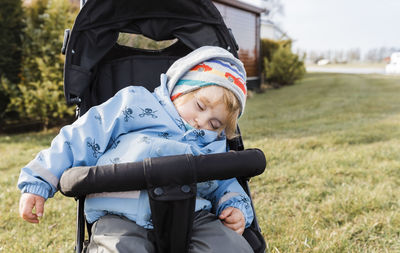 Girl sleeping on baby stroller at field