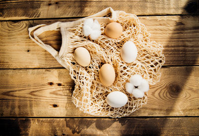 Easter concept. beige mesh shopping bag with brown chicken eggs on a wooden background.