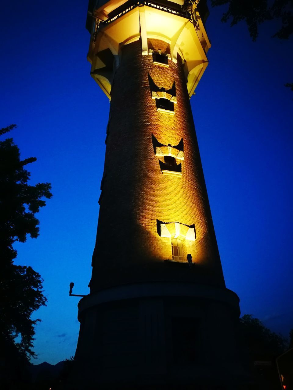 LOW ANGLE VIEW OF ILLUMINATED TOWER AGAINST CLEAR SKY AT NIGHT