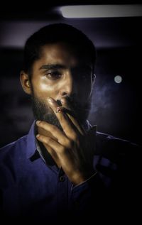 Young man looking away while smoking cigarette