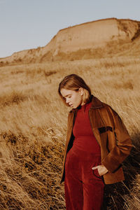 Side view of woman standing on field against sky