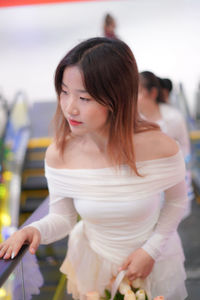 Portrait of young woman standing against wall