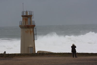 Rear view of man standing on shore against sea