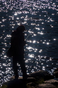 Side view of man standing by illuminated trees at night