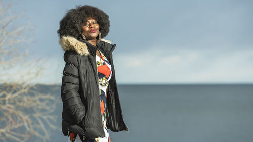 Young woman standing against sea