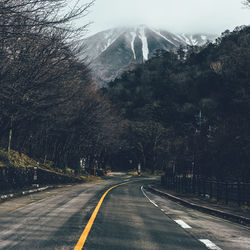 Road amidst trees against mountain