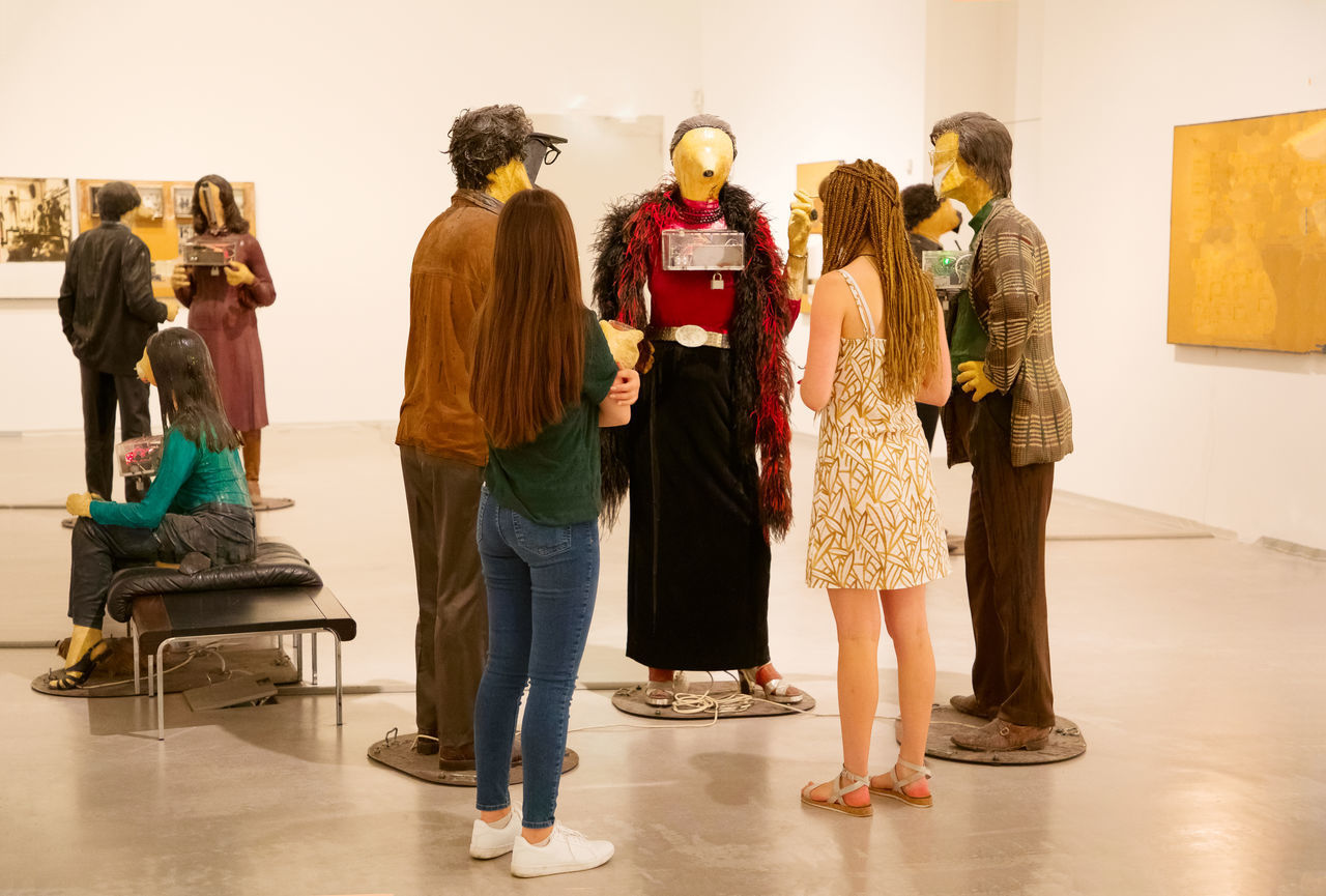 REAR VIEW OF PEOPLE STANDING IN THE DARK ROOM