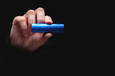 Cropped hand of person using mobile phone against black background