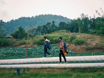 Full length of men walking on railing against trees