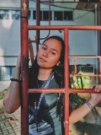 Portrait of young woman standing by metal