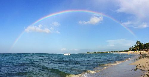 Scenic view of rainbow over sea against sky