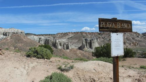 Information sign on rock formation against sky