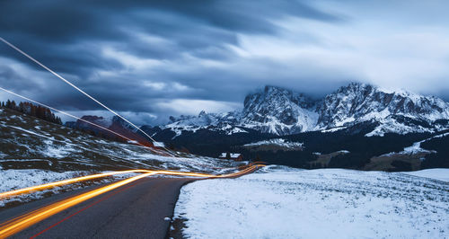 Road amidst snowcapped mountains against sky during winter