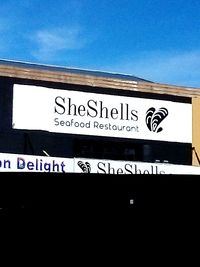 Low angle view of sign against blue sky