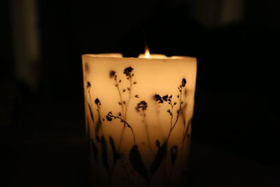 Close-up of lit tea light candle against black background
