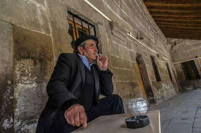 Full length of a man sitting in front of a wall