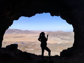 Silhouette woman standing on rock against sky