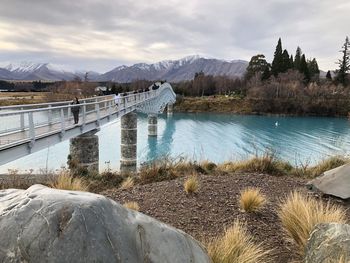 Scenic view of river by mountains against sky