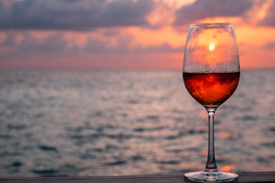 Wineglass against sea during sunset