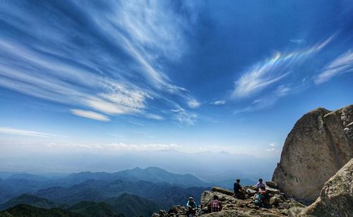 People on mountain against cloudy sky