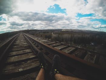 Person on railroad track against sky