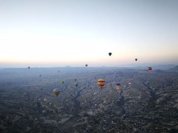 Hot air balloons flying over landscape against sky