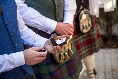 Midsection of man holding wedding rings while standing by friends