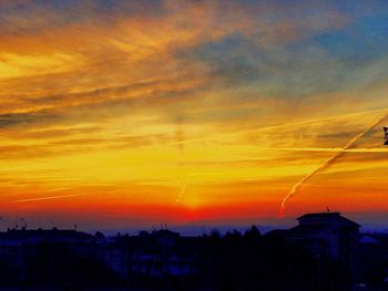 Silhouette cityscape against dramatic sky during sunset