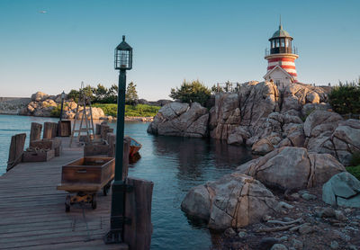 Lighthouse by sea against clear sky