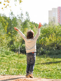 Little boy make gesture of happiness. toddler greets forest at city suburbans. nature vs town.