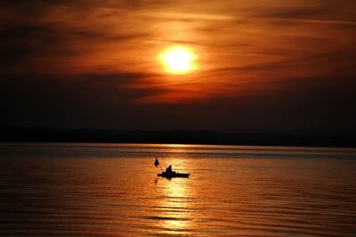 Silhouette boat in sea against sky during sunset