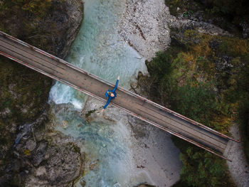 Austria, lower austria, annaberg, drone view of female hiker standing with raised arms on bridge stretching over otscherbach river