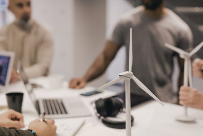 Close-up of windmill models on desk with business people in background