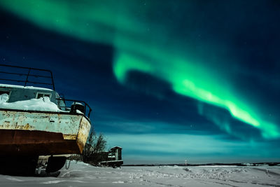 Abandoned cars on snow covered land against sky at night