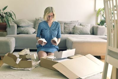 Woman holding shoes while kneeling at home