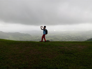 Man standing on mountain against cloudy sky