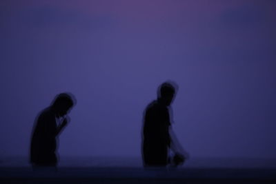 Side view of silhouette people against blue sky at night