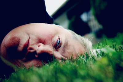 Close-up portrait of serious woman lying on grass