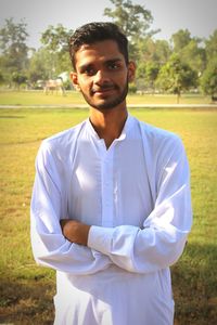 Portrait of young man standing against trees