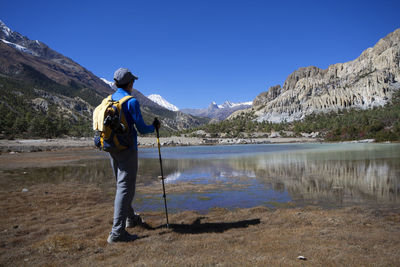 Rear view of man standing by lake against sky