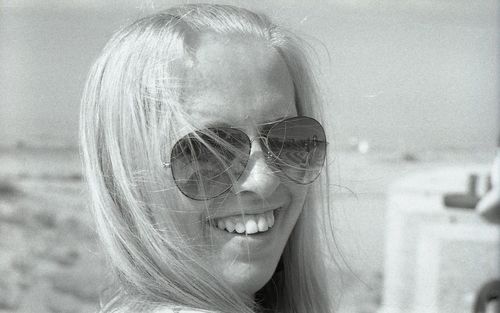 Close-up of happy woman wearing sunglasses against sky