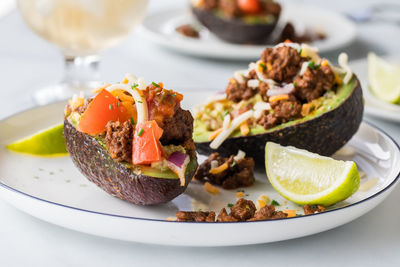 Avocado boats filled with taco ingredients including seasoned beef and cheese.