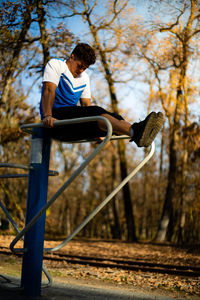 Man exercising on metal against trees