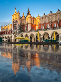 Reflections of cloth hall sukiennice building at sunrise on main square of krakow city, poland