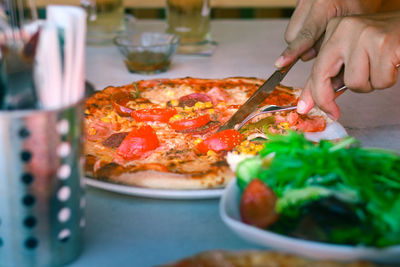 Close-up of hand holding pizza on table